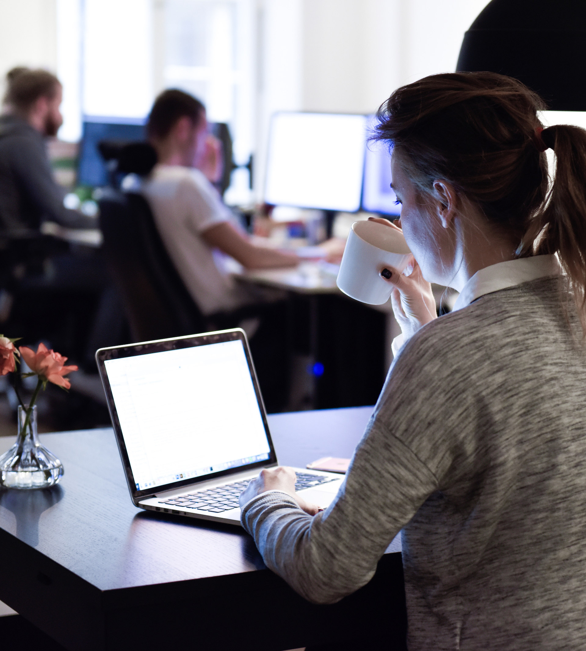 Kvinna framför dator med kontor i bakgrunden
