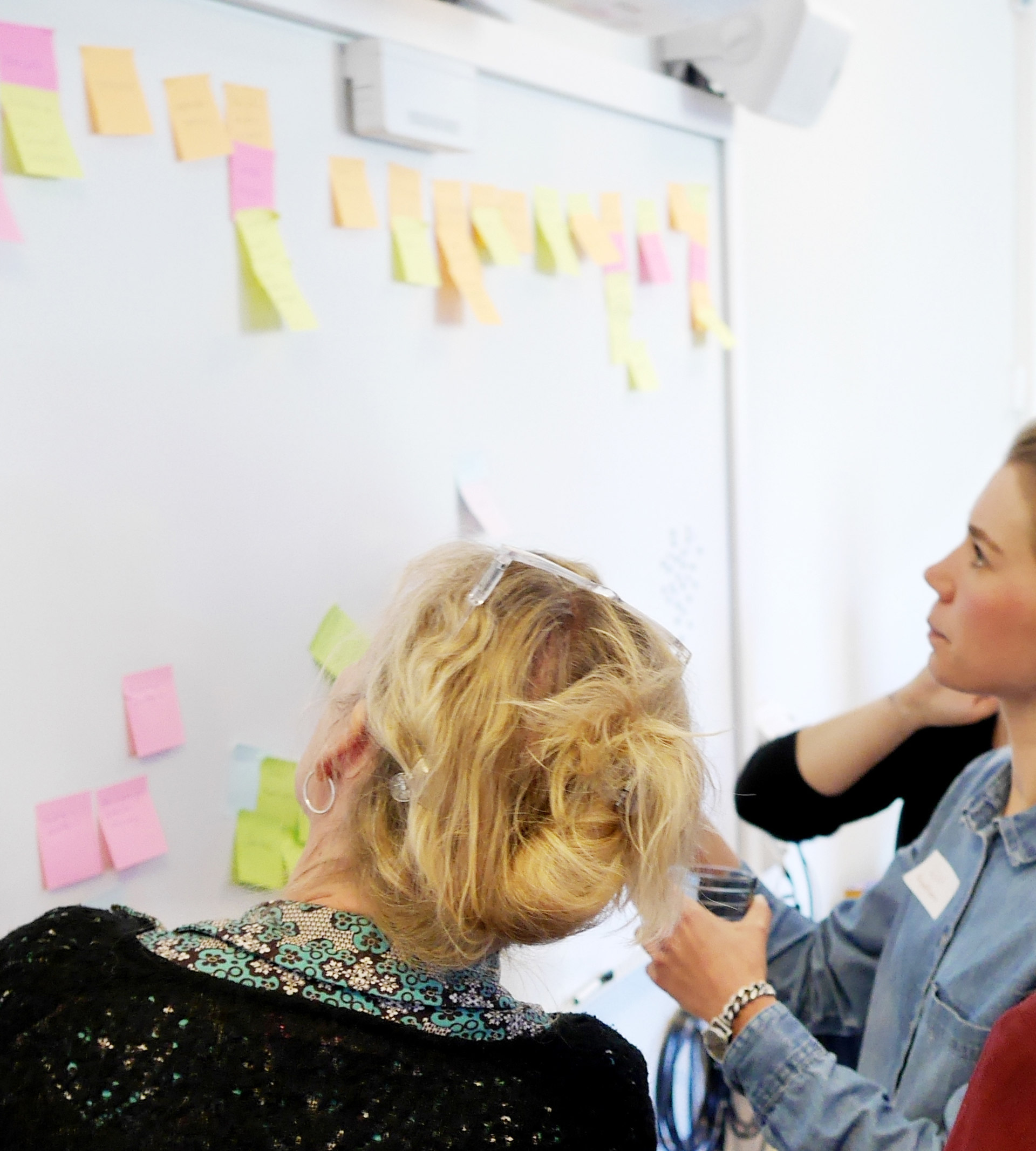 Två kvinnor framför en whiteboard med post-it
